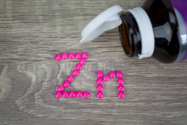 ピンク錠剤成形形状ウッドの背景に zn アルファベットに - zinc mineral nutritional supplement pill ストックフォトと画像