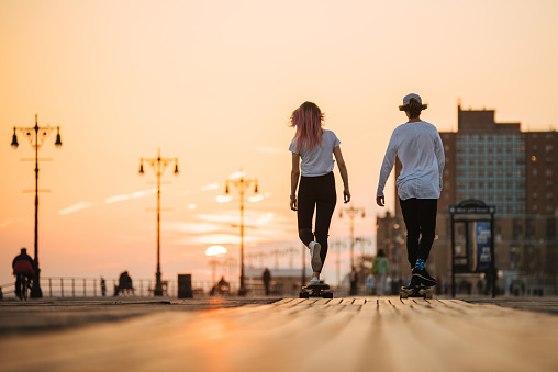 Teenagers ride longboards on the street from the back