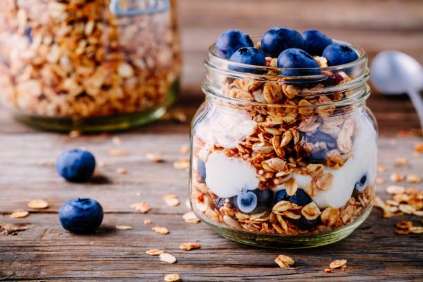 gesundes frühstück-parfait mit joghurt, hausgemachtem müsli und frischen bluberries in glas - jar oatmeal granola glass stock-fotos und bilder