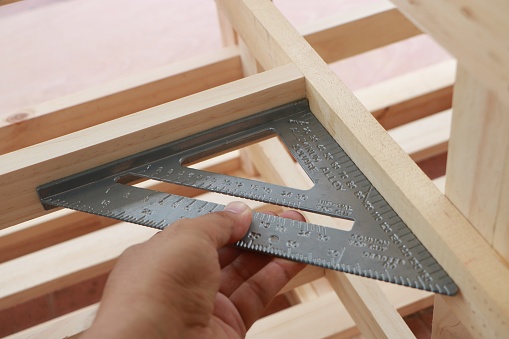 Hand of carpenter is measuring angle of wooden furniture