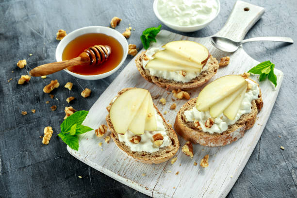 istock Appetizer bruschetta with pear, honey, walnut and cottage cheese on white board. 688502746
