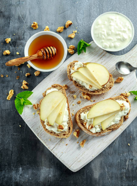 istock Appetizer bruschetta with pear, honey, walnut and cottage cheese on white board. 688502816