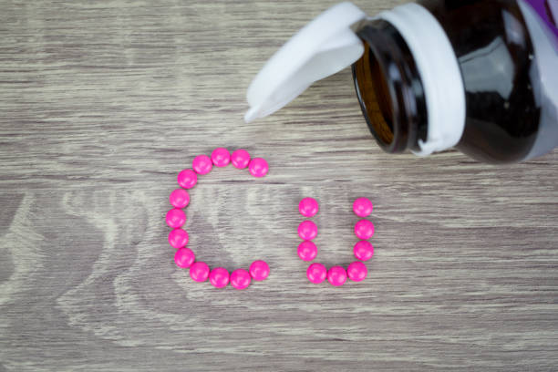 istock Pink pills forming shape to Cu alphabet on wood background 688526412