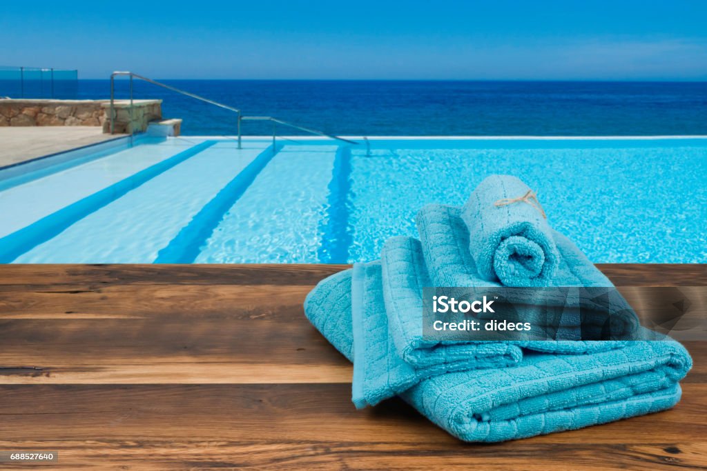 Towels on wooden over blurred swimming pool and sea background Towel Stock Photo