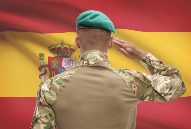 Dark-skinned soldier with flag on background - Spain stock photo
