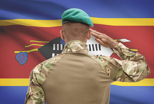 Dark-skinned soldier in hat facing national flag series - Swaziland