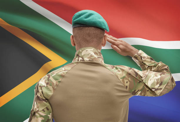 Dark-skinned soldier with flag on background - South Africa stock photo