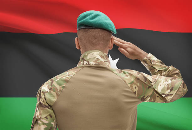 istock Dark-skinned soldier with flag on background - Libya 688541548