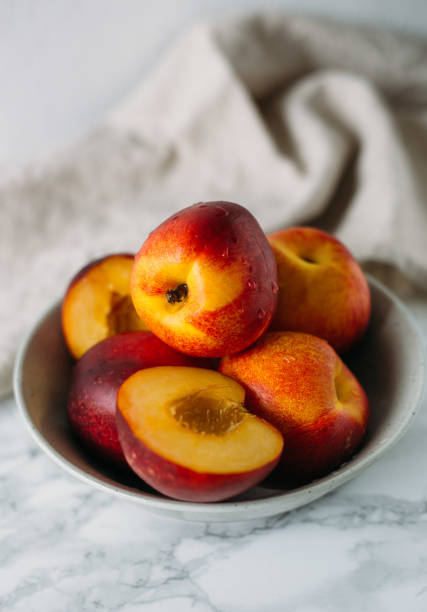 istock Ripe peaches in bowl on marble background 688547426