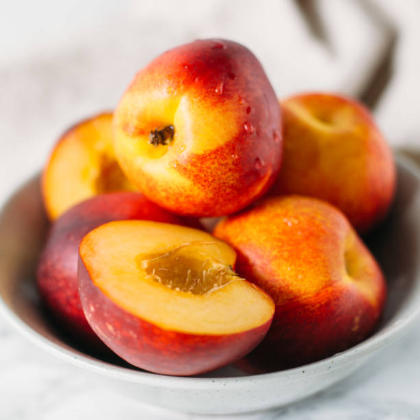 istock Ripe peaches in bowl on marble background 688547600