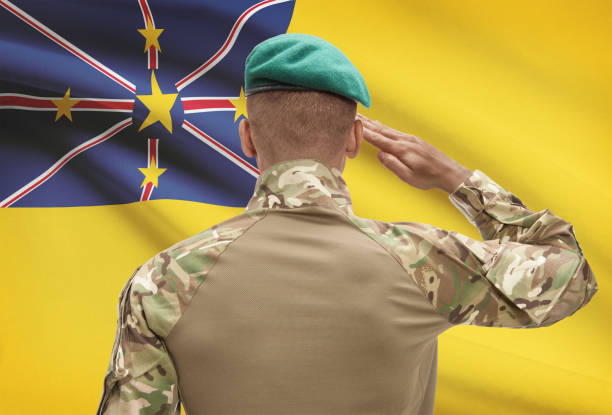 istock Dark-skinned soldier with flag on background - Niue 688547946