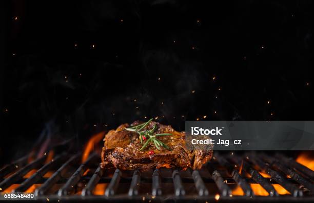 Beef Steak On The Grill Grate Flames On Background Stock Photo - Download Image Now