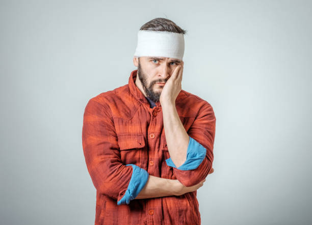 Portrait of man with bandages wrapped around his head isolated on gray background Portrait of man with bandages wrapped around his head isolated on gray background bandage stock pictures, royalty-free photos & images