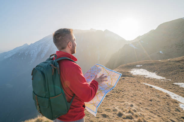 istock Young man hiking in Switzerland looking at map 688554424