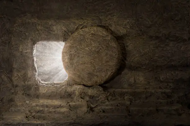 The tomb of jesus with stone rolled away and light coming from inside