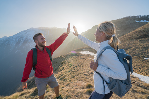 Two hikers celebrating on mountain trail with an high five. Shot in Switzerland, Springtime.