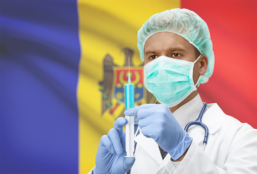 Doctor with syringe in hands and flag on background - Moldova