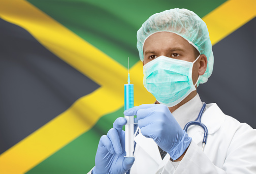 Doctor with syringe in hands and flag on background - Jamaica