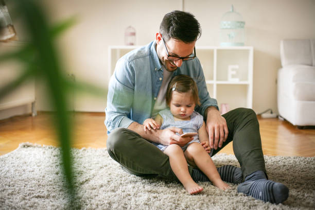 single father wit his daughter using smart phone. father and little baby watching something funny at smart phone. - father fathers day baby child imagens e fotografias de stock