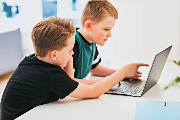 Children working together in front of laptop computer stock photo