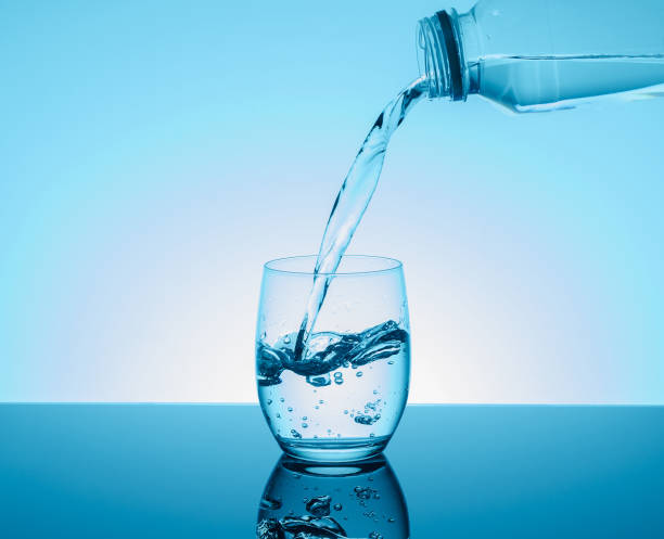 Bottle with creative splashing water in the glass