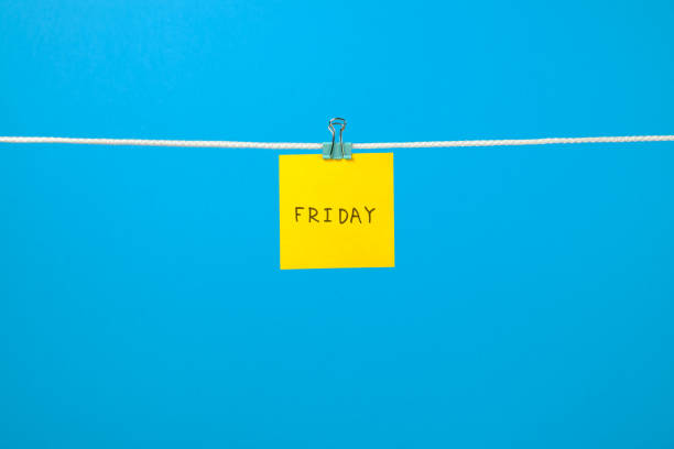 istock Yellow paper note on clothesline with text Friday over colorful background 688577804