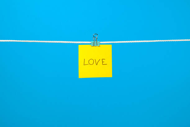 istock Yellow paper note on clothesline with text Love over colorful background 688577816