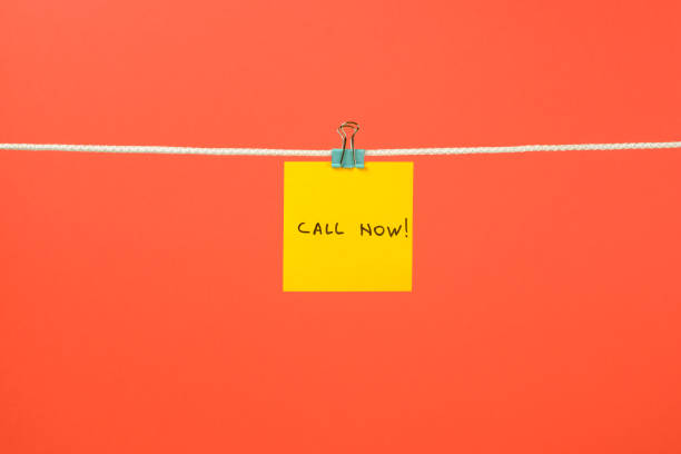 istock Yellow paper note on clothesline with text Call Now! over colorful background 688577828