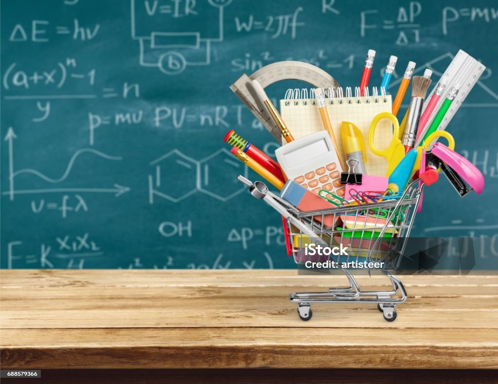 Education. Variety office supplies in little shoping cart with green chalk board on background Cart Stock Photo