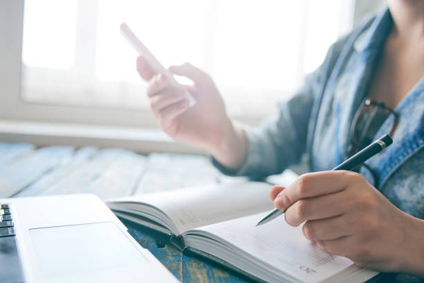 istock Person writing notes and working on the phone 688579788