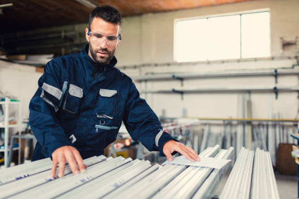 Aluminium and PVC industry worker looking instructions manual for window and door frames in factory