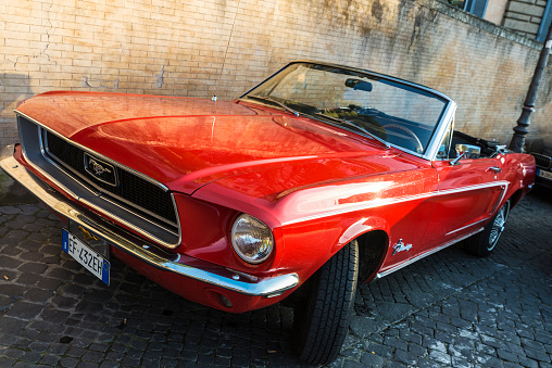 Rome: Ford Mustang convertible red of the year 1964 parked on a street in the historical center of Rome, Italy.