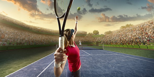 Female sportsman is playing tennis on an outdoor stadium full of spectators. She is wearing unbranded sports cloth and using unbranded sport equipment