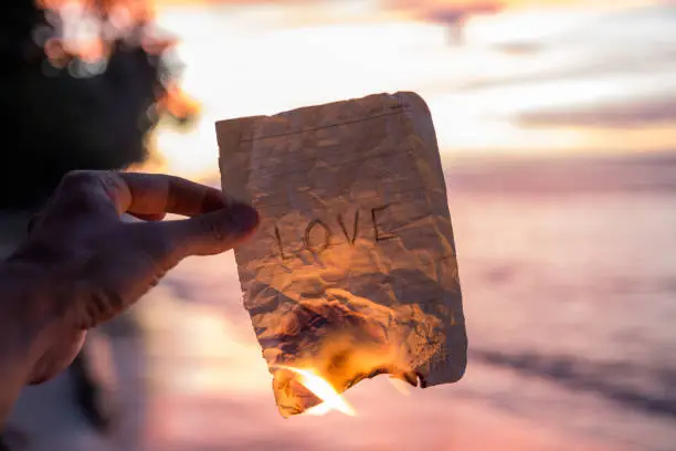 Hand holding a burning paper with word Love