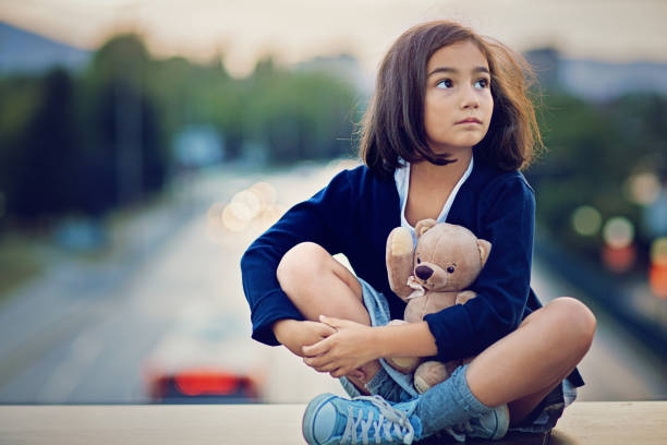 istock Little girl is standing sad on the bridge 688599910