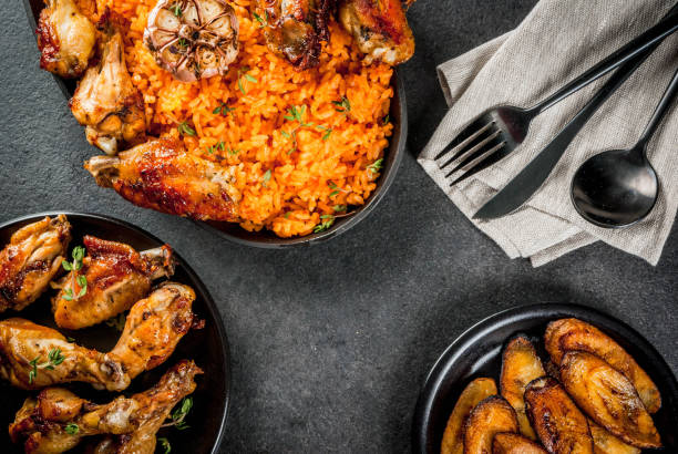 Jollof rice with chicken and plantains West African national cuisine. Jollof rice with grilled chicken wings and fried bananas plantains.On gray stone table. Copy space  top  view ghana photos stock pictures, royalty-free photos & images