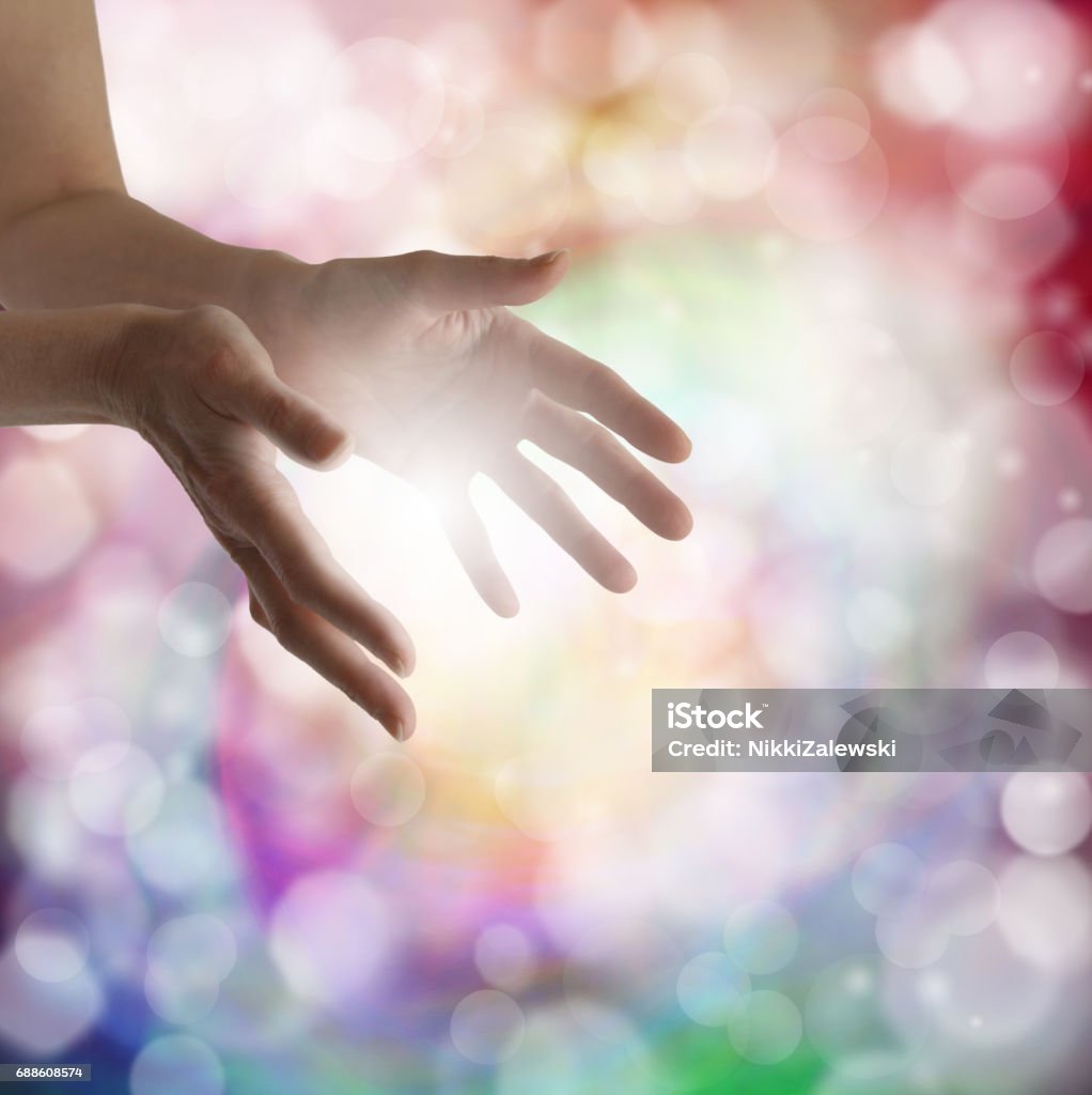 Sensing soft healing energy Woman's outstretched healing hands with light bokeh background and white energy between hands Reiki Stock Photo