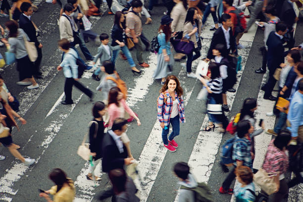 joven caucásica está sonriendo confuso curarle en multitud de tokio - missing in action fotografías e imágenes de stock