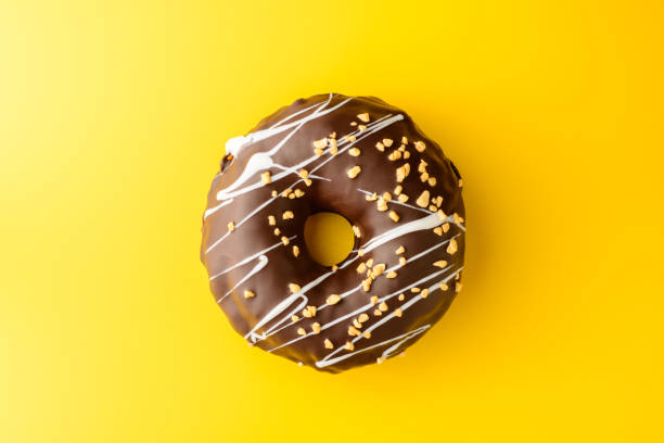 istock Chocolate donut on bright yellow background. 688610788