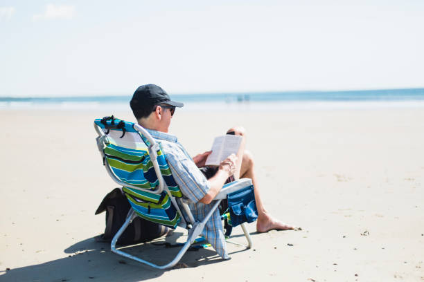 istock A man sitting on a beach chair on the beach and reading a book 688636056