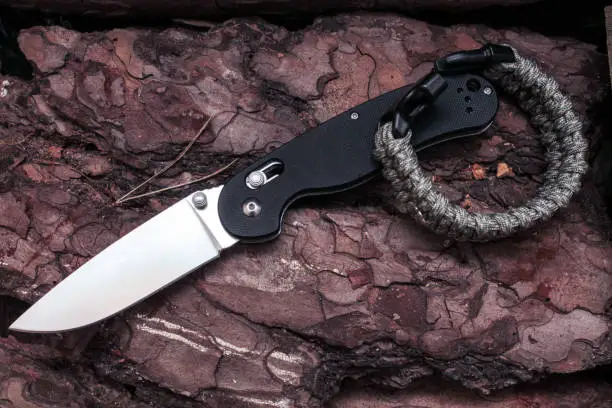 Photo of Knife with a tactical bracelet. Bracelet made of paracord. Parachute cord.