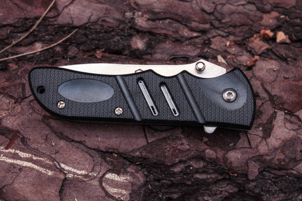 istock Pocket knife on the pine bark. Knife with stripes on the handle. Tree. The black. 688661168