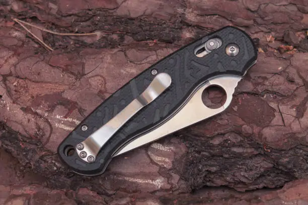 Photo of Folded knife against the background of pine bark.