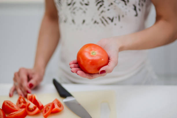 istock woman's hand holding a red ripe tomato. 688725316