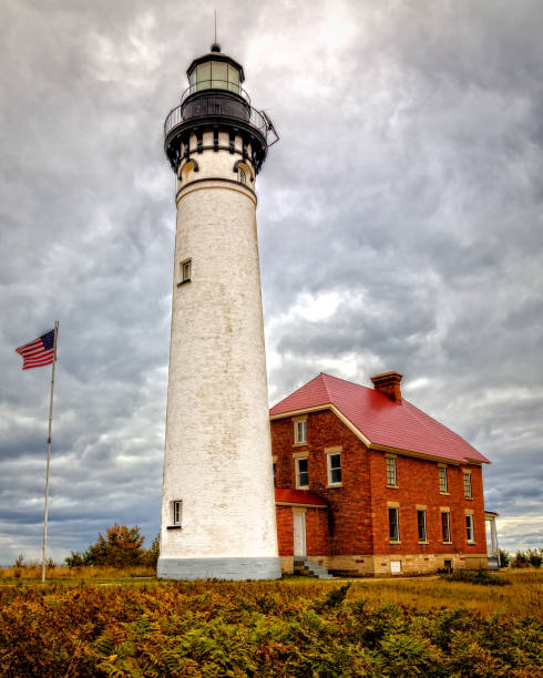 istock Au Sable Lighhouse with Waving Flag, clouds, red brick vertical 688730946