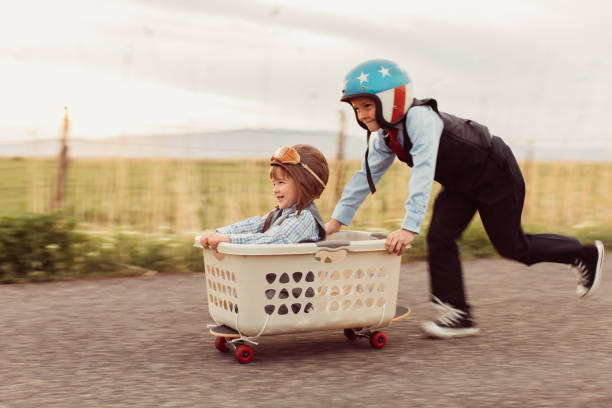 dwóch młodych chłopców biznesu wyścigi na deskorolce - car child teamwork sports race zdjęcia i obrazy z banku zdjęć