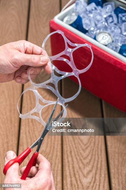 Photo libre de droit de Anneaux En Plastique De Six Packs Coupe Les Mains Mâle Avec Des Ciseaux banque d'images et plus d'images libres de droit de Pack de six