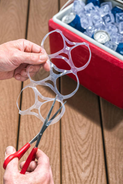 Male hands cutting plastic Six-Packs rings with scissors