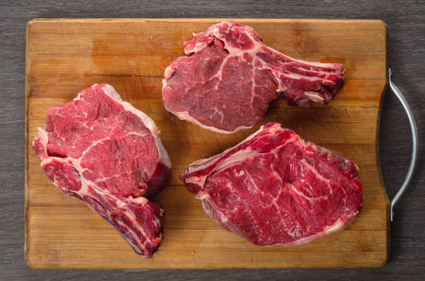 istock Raw Bone-in Rib eye Steak on wooden background 688761554