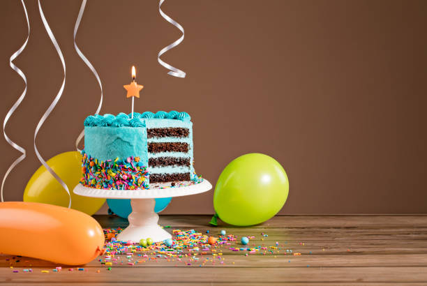 Birthday Cake with Balloons Chocolate birthday cake with blue buttercream icing and colorful balloons on a brown background. birthday cake green stock pictures, royalty-free photos & images